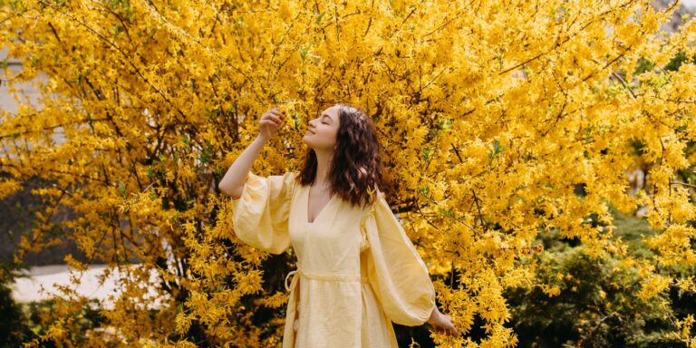 woman in yellow dress by forsythia flowers