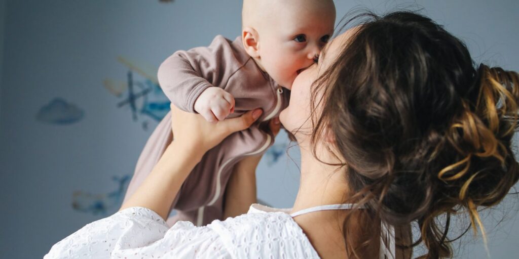mom holding kissing baby in air